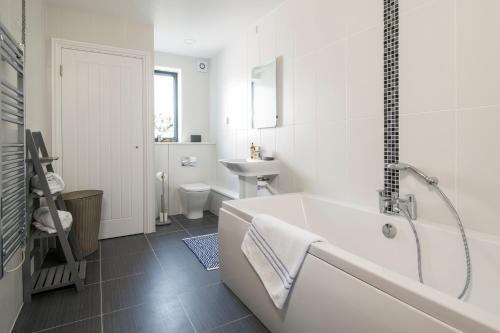 ein weißes Badezimmer mit Badewanne und Waschbecken in der Unterkunft Cedar Lodge in Carbis Bay