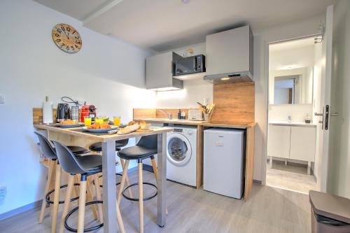 a kitchen with a counter and a table with chairs at Le Sabot - Netflix/Wi-Fi Fibre/Terasse - 4 pers in Banassac