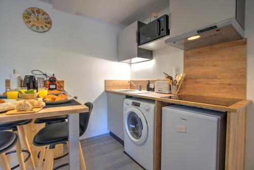 uma cozinha com máquina de lavar e secar roupa ao lado de um balcão em Le Sabot - Netflix/Wi-Fi Fibre/Terasse - 4 pers em Banassac