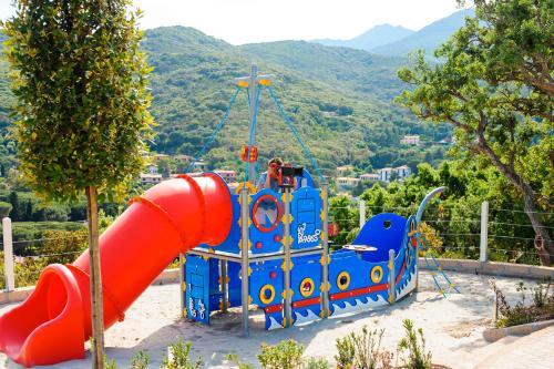 a playground with a red slide in a park at Hotel La Perla Del Golfo in Procchio