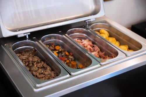three trays of food sitting in an oven at Hotel Mecenate Palace in Rome