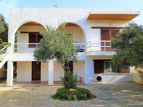 a white building with a tree in front of it at Gianna Seaside in Koutsounari
