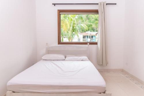 - un lit blanc dans une chambre avec fenêtre dans l'établissement Recanto de Ubatuba, à Ubatuba