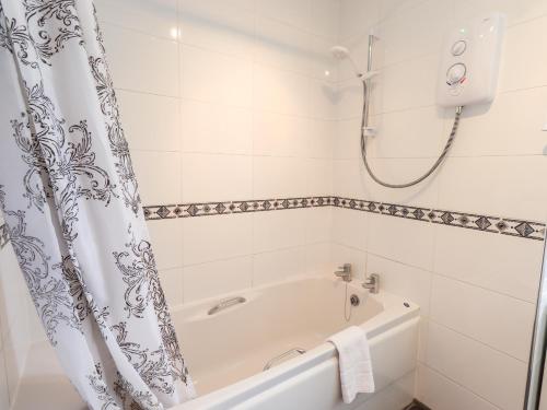 La salle de bains blanche est pourvue d'une baignoire et d'une douche. dans l'établissement Birch Knoll, à Ambleside