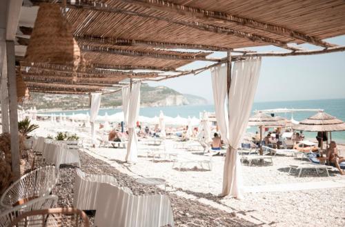 a beach with white tables and chairs and the ocean at Agriturismo Giorgio in Mattinata