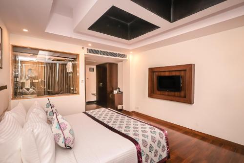 a bedroom with a white bed and a tv at Regenta Resort MARS Valley View Shoghi in Shimla