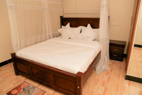 a bed with white sheets and pillows in a room at Scindia Suites hotel in Jinja