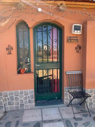 a green door on a pink building with a chair at Cabaña Girasoles Mi Campito Cachi Salta in Cachí
