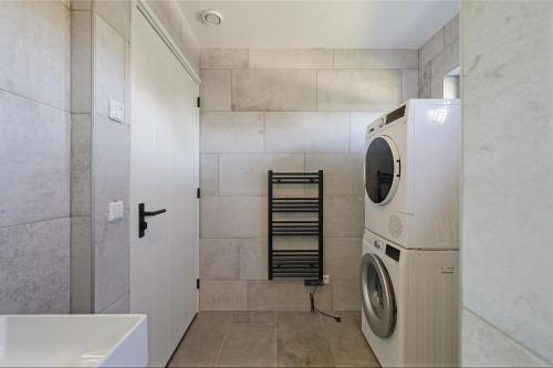 een badkamer met een wasmachine en een wastafel bij Vuurtorenveld 136 - Het Oude Nieuwland Ouddorp - NOT FOR COMPANIES in Ouddorp