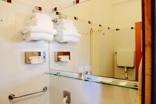 a bathroom with a mirror and a pile of towels at Arcangelo Roof Hotel in Rimini