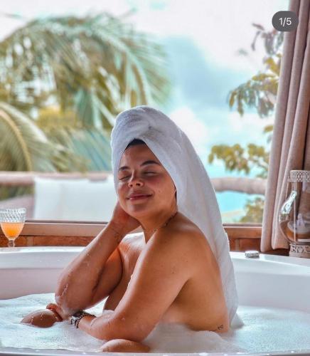 a man sitting in a bathtub with a towel on his head at Chalés Paraty Real in Paraty