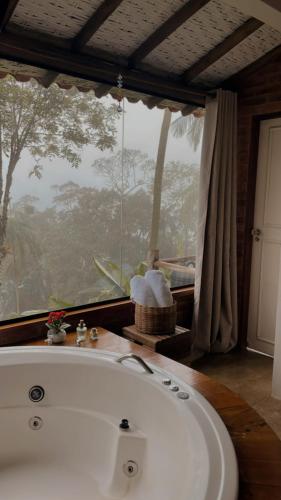 a bath tub in a bathroom with a large window at Chalés Paraty Real in Paraty