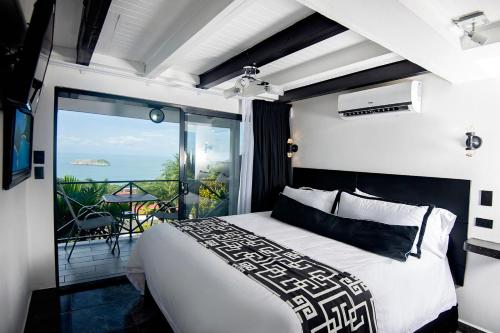 a bedroom with a bed and a view of the ocean at Villa Roca Boutique Resort & Suites - ADULT ONLY in Manuel Antonio