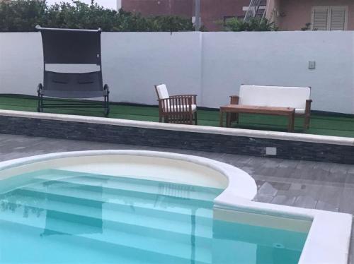 a swimming pool with two chairs and a bench in a backyard at Lemon Gold in Locogrande