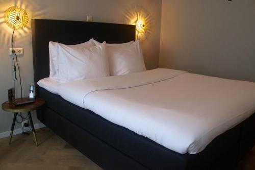 a bed with white sheets and pillows in a hotel room at Hotel Karsten in Norg