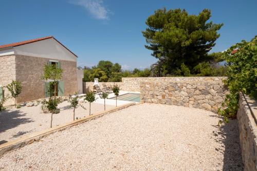 a stone wall next to a building with a yard at BRAND NEW Stone house MARCELA, 3 double bedrooms, pool in Lun