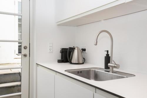 a kitchen with white cabinets and a sink at Idyllisk lejlighed med plads til 4-personer in Højbjerg