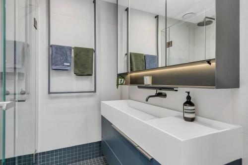 uma casa de banho com um lavatório branco e um espelho. em Sol Docklands - Unique 3 Bedroom Loft, Infinity Pool, Gym, Free Parking and Free Trams em Melbourne