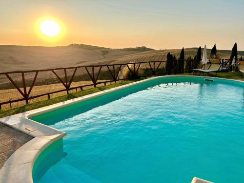 a swimming pool with the sunset in the background at Podere Poggio Salto in Pienza