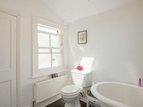 a white bathroom with a toilet and a tub at Charming 2 double bed cottage style house in Bristol