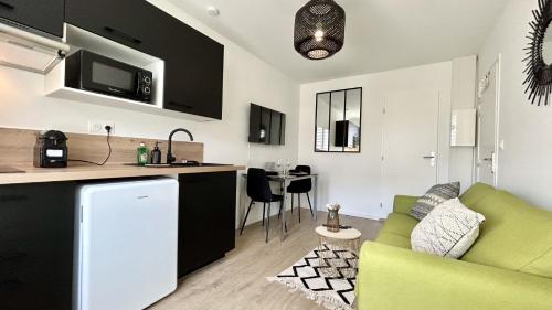 un salon avec un canapé vert et une cuisine dans l'établissement L'Escale, à Fort-Mahon-Plage