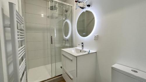 une salle de bain blanche avec un lavabo et un miroir dans l'établissement L'Escale, à Fort-Mahon-Plage