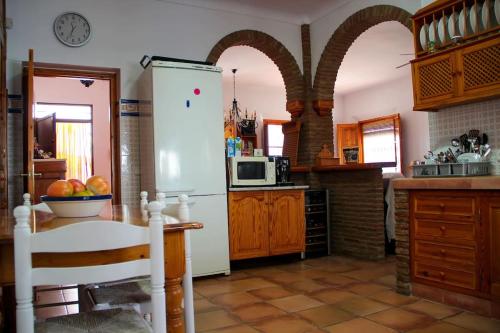 uma cozinha com um frigorífico e uma mesa com uma taça de fruta em Casa Rural Lomillas de Canca em Álora