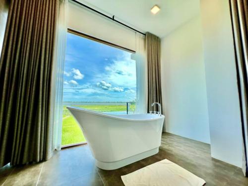 La salle de bains est pourvue d'une baignoire et d'une grande fenêtre. dans l'établissement Blue Wild - Yala - Plastic Free & Sustainable, à Tissamaharama