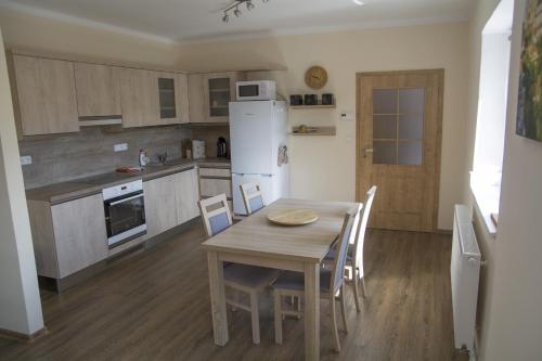 eine Küche mit einem Holztisch und einem weißen Kühlschrank in der Unterkunft Domek u Dyje in Znojmo