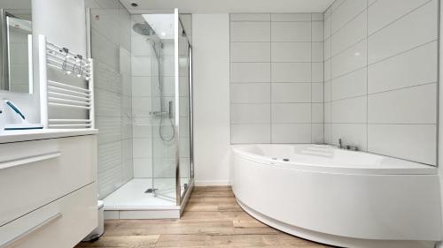 une salle de bain blanche avec une baignoire et une douche dans l'établissement L'Horizon, à Fort-Mahon-Plage