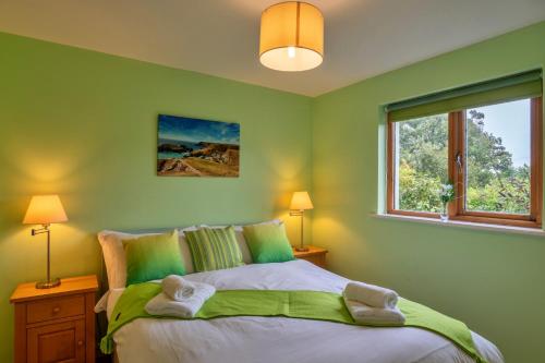 a green bedroom with a bed and a window at Finest Retreats - Skylarks in Boscastle