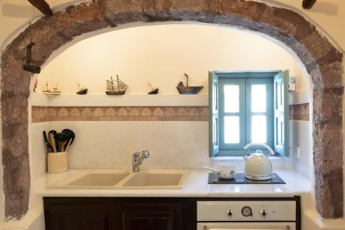 una cocina con fregadero y ventana en Villa Historia, en Oia