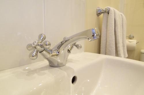 a white sink with a silver faucet in a bathroom at The Baytree - Exclusively for Adults in Torquay