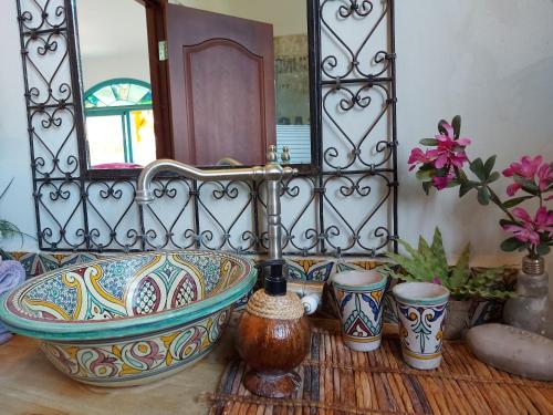 a bathroom with a sink and a mirror and some vases at Zehava's Zimmer in Ein Gedi