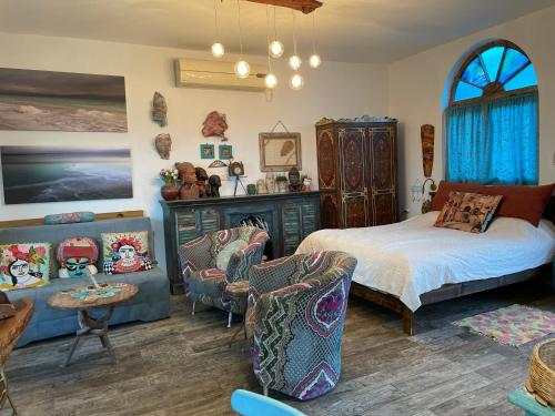 a bedroom with a bed and a couch and chairs at Zehava's Zimmer in Ein Gedi