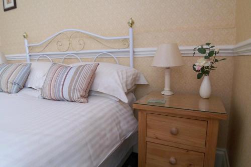 a bedroom with a bed with a lamp and a dresser at The Baytree - Exclusively for Adults in Torquay