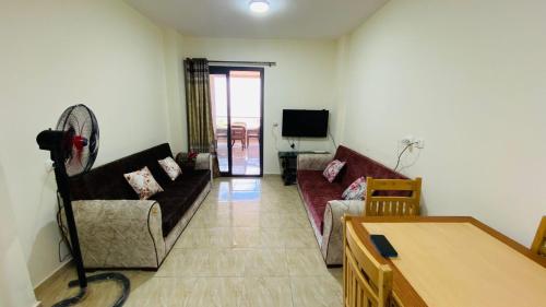 un soggiorno con 2 divani e una TV di جراند هيلز الساحل الشمالي Grand Hills North Coast شالية فندقي H047 عائلات فقط a Dawwār ‘Abd Allāh
