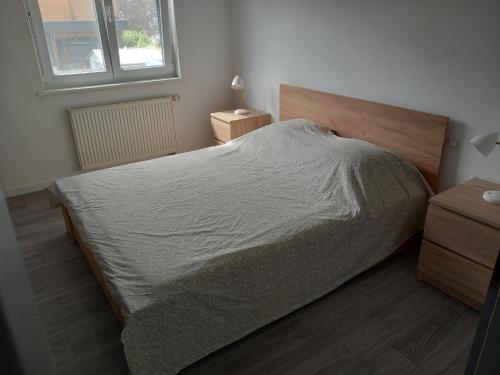 Schlafzimmer mit einem Bett mit einem Kopfteil aus Holz und einem Fenster in der Unterkunft Appartement 3 pièces avec balcon in Rhinau