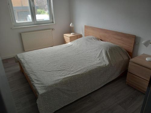 une chambre avec un lit avec une tête de lit en bois et une fenêtre dans l'établissement Appartement 3 pièces avec balcon, à Rhinau