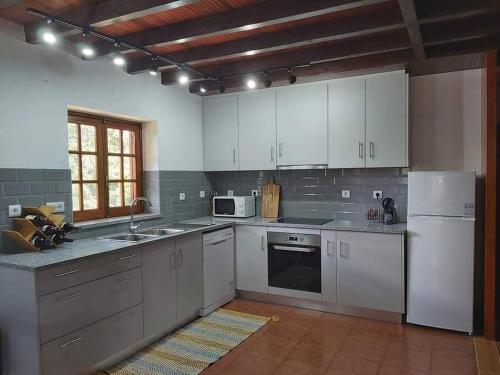 a kitchen with white cabinets and a white refrigerator at Casa Vale Nicolau in Arganil