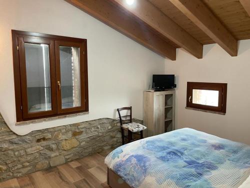 1 dormitorio con cama y pared de piedra en Antico Borgo le Roste en Sassomorello