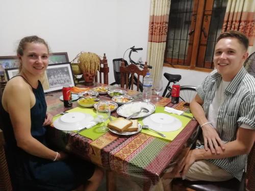 Ein Mann und eine Frau sitzen an einem Tisch mit Essen in der Unterkunft BAS Balcony in Anuradhapura