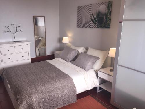 a bedroom with a large bed and a mirror at Casa de Ferias Arrifes in Cascais