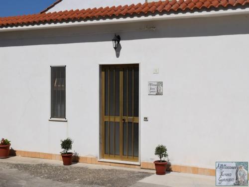 a white building with a brown door and two plants at casa vacanze nonnogennaro in Matonti