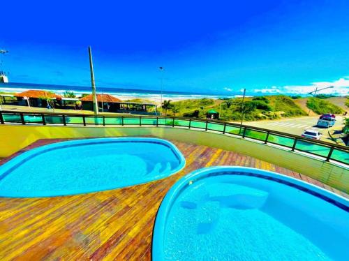 two hot tubs on a deck with a view of the ocean at LOFT ORLA PRAIA GRANDE até 5 pessoas in Arraial do Cabo