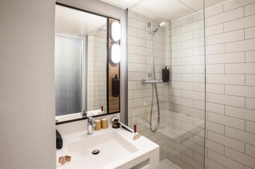 La salle de bains est pourvue d'un lavabo et d'une douche en verre. dans l'établissement ibis Strasbourg Centre Les Halles, à Strasbourg