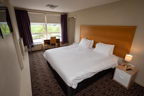 una habitación de hotel con una cama grande y una mesa en The Titan, en Clydebank