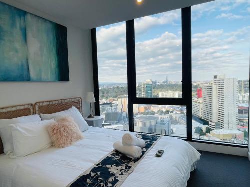 uma cama num quarto com uma grande janela em Free Parking-Luxurious & Spacious Skyline view Apt em Melbourne