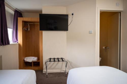 a room with two beds and a flat screen tv at The Titan By Greene King Inns in Clydebank