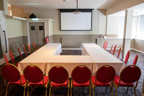 a conference room with a table and chairs and a screen at The Titan By Greene King Inns in Clydebank